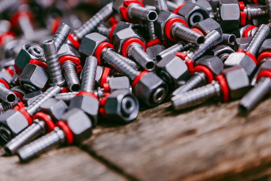 Ein Stapel Metallbolzen mit roten und schwarzen Gummiringen auf einer Holzoberfläche, der industrielle Hardwarekomponenten zur Schau stellt.
